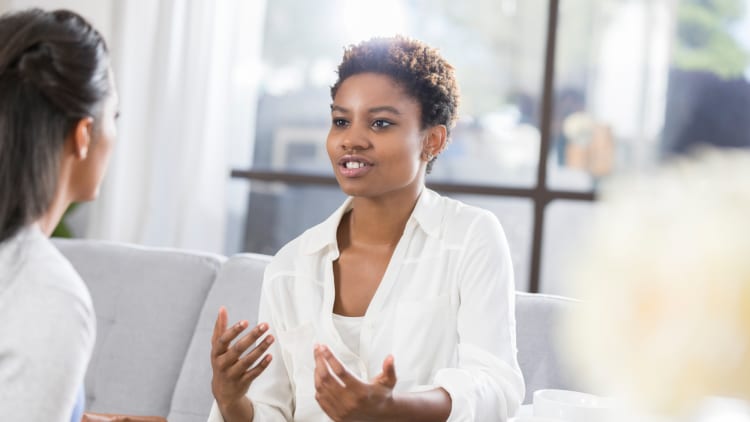 african american woman sitting on soft sofa in a well lit room being interviewed by a behavioral health therapist for insomnia sleep issues